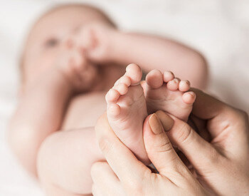 Mutter massiert sanft die Fußreflexzonen Ihres Babys